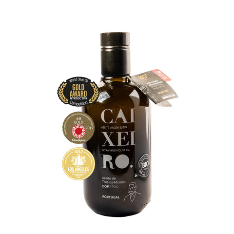 huile d'olive vierge extra dans ue bouteille en verre foncé avec lettres blanches et labels de récompense concours, vue frontale