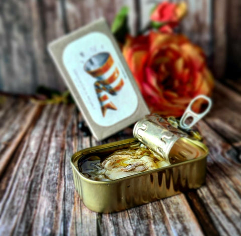 conserve de morue en huile d'olive et ail sur une table en bois massif avec rose en arrière-plan