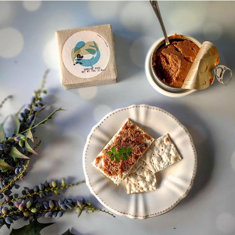 cracottes avec pâté de thon sur une assiette blanche entourée de fleurs, conserve ouverte avec une cuillère dedans