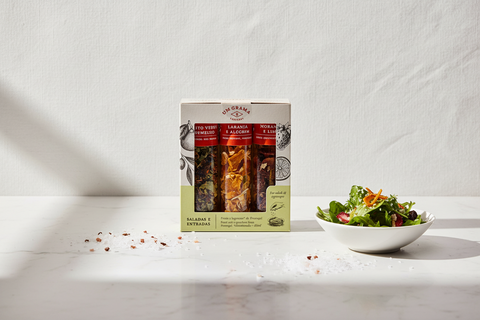 tubes de fruits et légumes déshydratés dans emballage en carton sur une table en marbre blanc et fond blanc texturé, petit bol blanc de salade à la droite et graines de sel sur la table