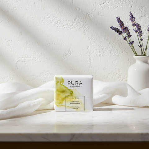 savon solide dans un emballage blanc et vert sur une table en marbre clair, drap en lin clair, fond en pierre blanche, vase en céramique blanc avec lavande