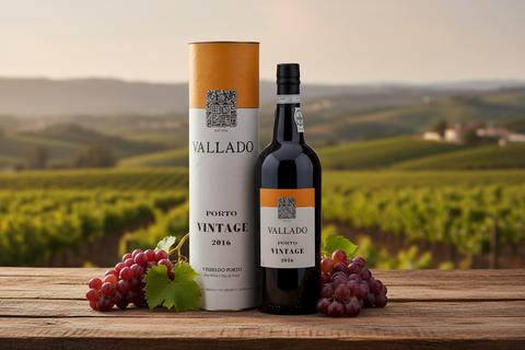 bouteille de vin de Porto Vallado Vintage sur une table en bois avec raisins rouges et vignoble en arrière-plan